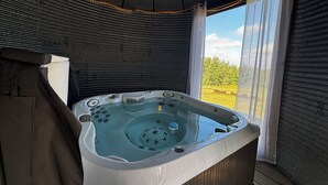 Ett bubbelbad i ett avskärmat utomhusområde med utsikt över ett fält.