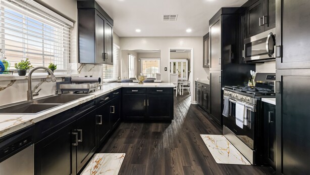 A modern kitchen with dark cabinetry, stainless steel appliances, and a marble backsplash.