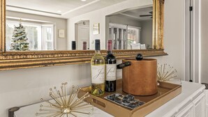 A well-lit room with a large mirror, a white countertop, and a tray with bottles and a copper pot.