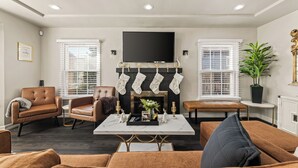 A modern living room with a fireplace, leather sofas, a coffee table, and a television.
