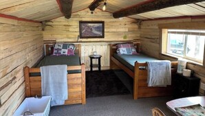 Una cabaña con dos camas literas de madera, una mesita, una silla y una ventana con vistas.
