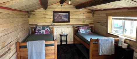 Una cabaña con dos camas literas de madera, una mesita, una silla y una ventana con vistas.