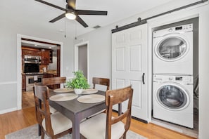 A dining area with a table, chairs, a ceiling fan, and a washing machine.