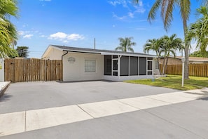A single-story house with a covered patio, a wooden fence, and a clear sky.
