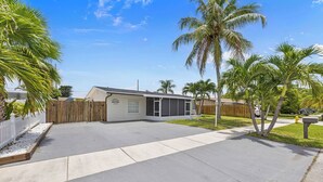 Uma propriedade residencial com garagem, quintal cercado e palmeiras.