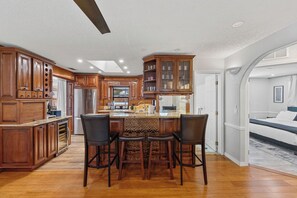 A spacious kitchen with wooden cabinets, a central island with bar stools, and a view into the adjacent living area. - 3-bedroom house in phenomenal Pompano Beach with nice relaxing pool with gazebo (Pompano Beach)