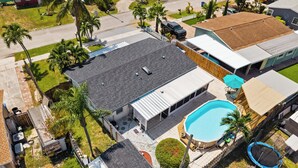 Um imóvel residencial com piscina, varanda coberta e quintal cercado.