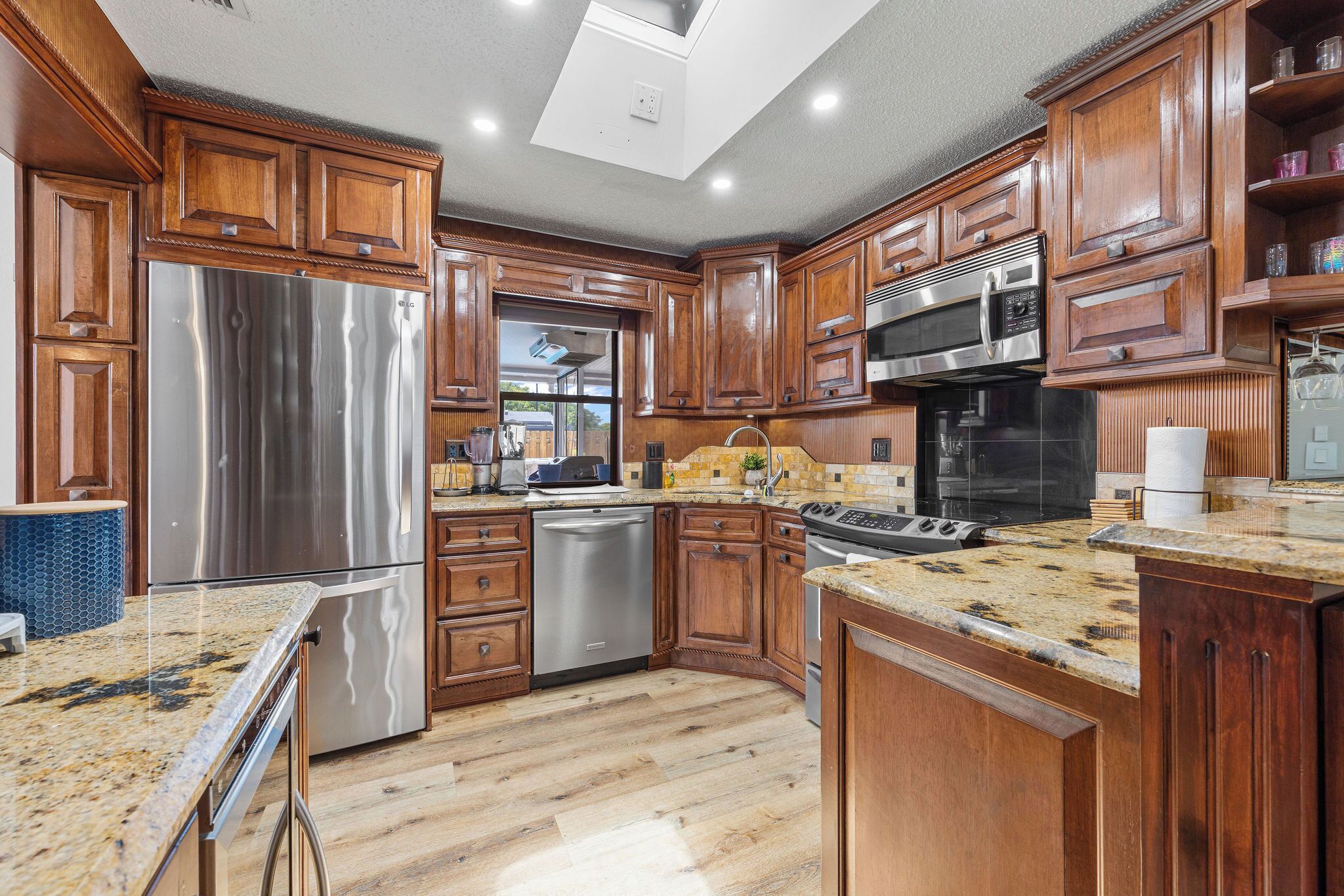 A modern kitchen with wooden cabinets, stainless steel appliances, and a granite countertop.