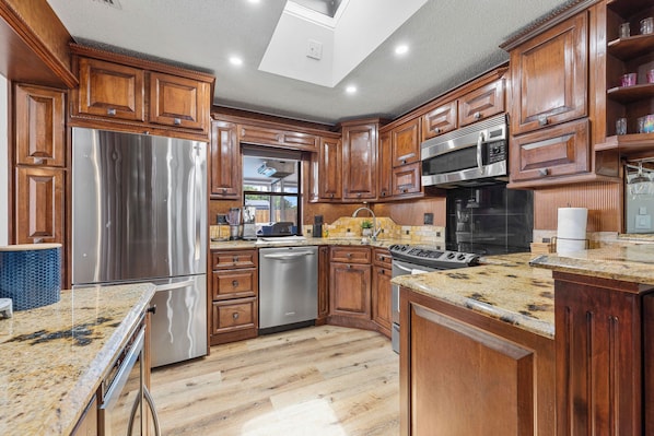 A modern kitchen with wooden cabinets, stainless steel appliances, and a granite countertop.