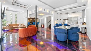 A spacious living area with a glossy floor, a modern kitchen, and a dining area with blue chairs. - Modern Retreat Near Atlantic Station (Atlanta)