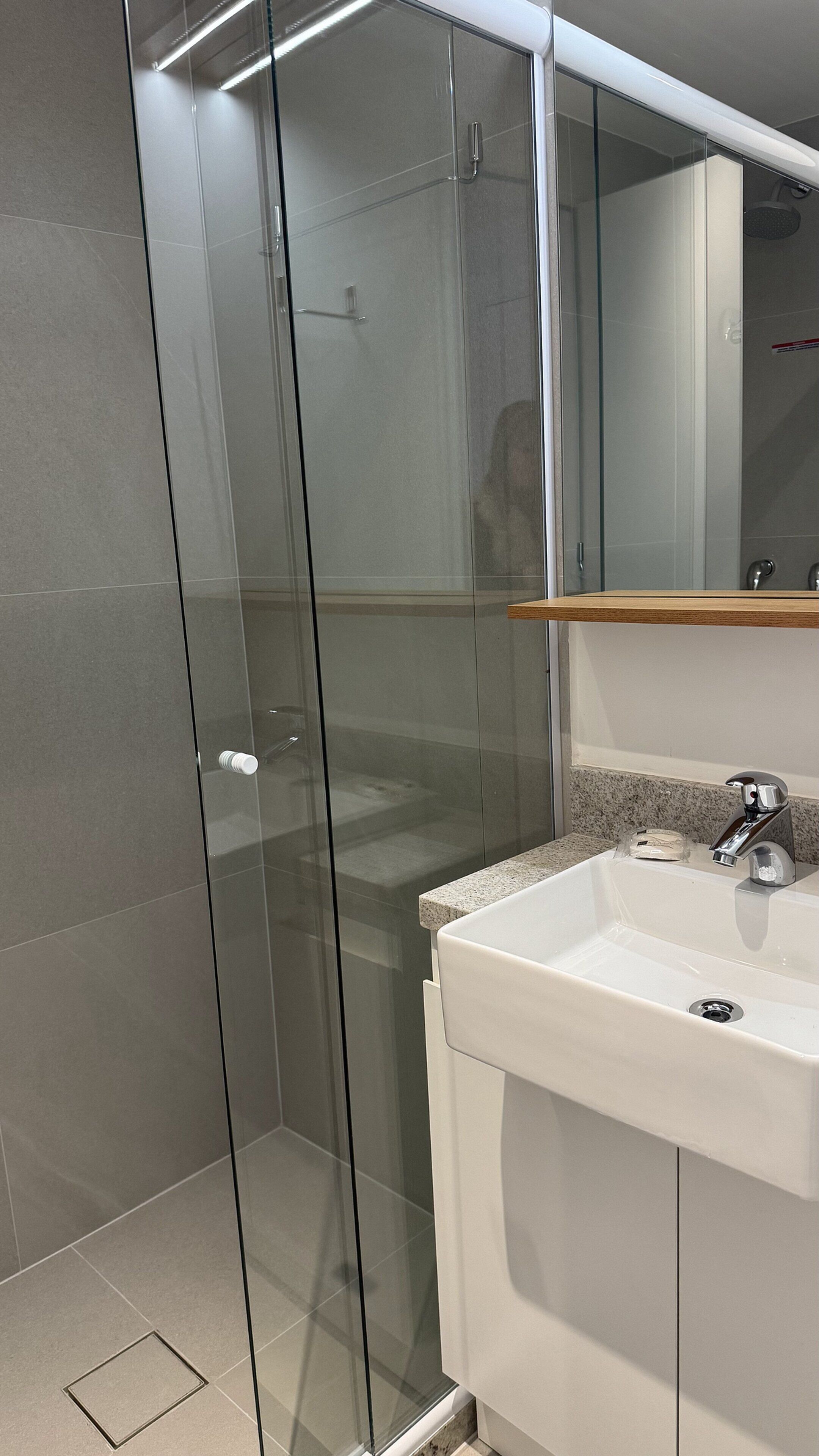 A modern bathroom with a glass shower enclosure, a white sink, and a mirror above the sink.