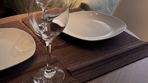A hotel room with a bed, a window with a city view, a framed flower painting, and a dining setup with a glass, plate, and cutlery. - Skyline (Porto Alegre)