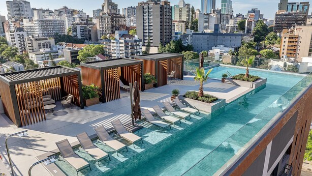 A rooftop pool with lounge chairs and a wooden pergola, overlooking a cityscape. - Skyline (Porto Alegre)