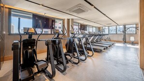 A gym with treadmills and ellipticals, large windows, and a high ceiling. - Skyline (Porto Alegre)