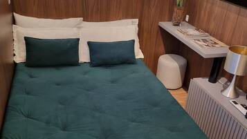 A modern bedroom with a bed, bedside table, lamp, and a TV mounted on the wall.
