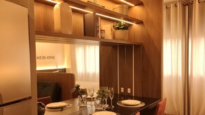 A modern dining area with a long table, chairs, and a built-in shelf with decorative items. - Skyline (Porto Alegre)
