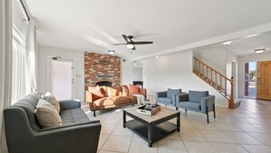 A spacious living room with a fireplace, two sofas, a coffee table, and a staircase.