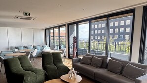 A spacious living area with a large sofa, a coffee table, and a dining table. There are large windows providing a view of the city. - GO CARLOS GOMES (Porto Alegre)