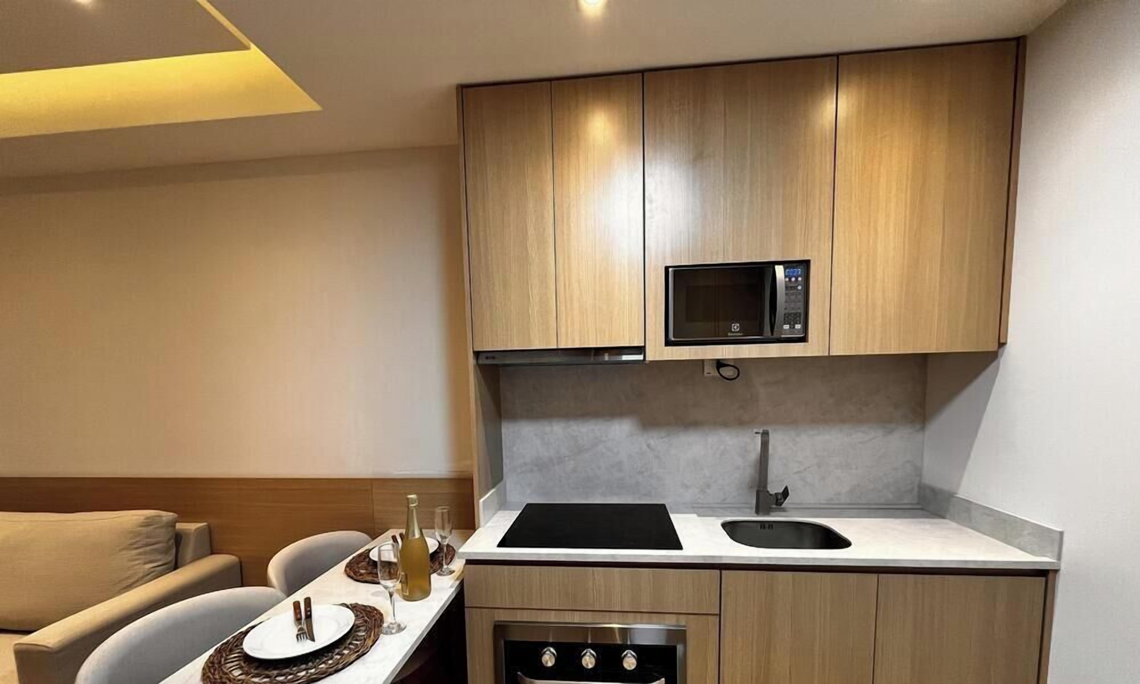 A compact kitchenette with a microwave, stove, and sink.