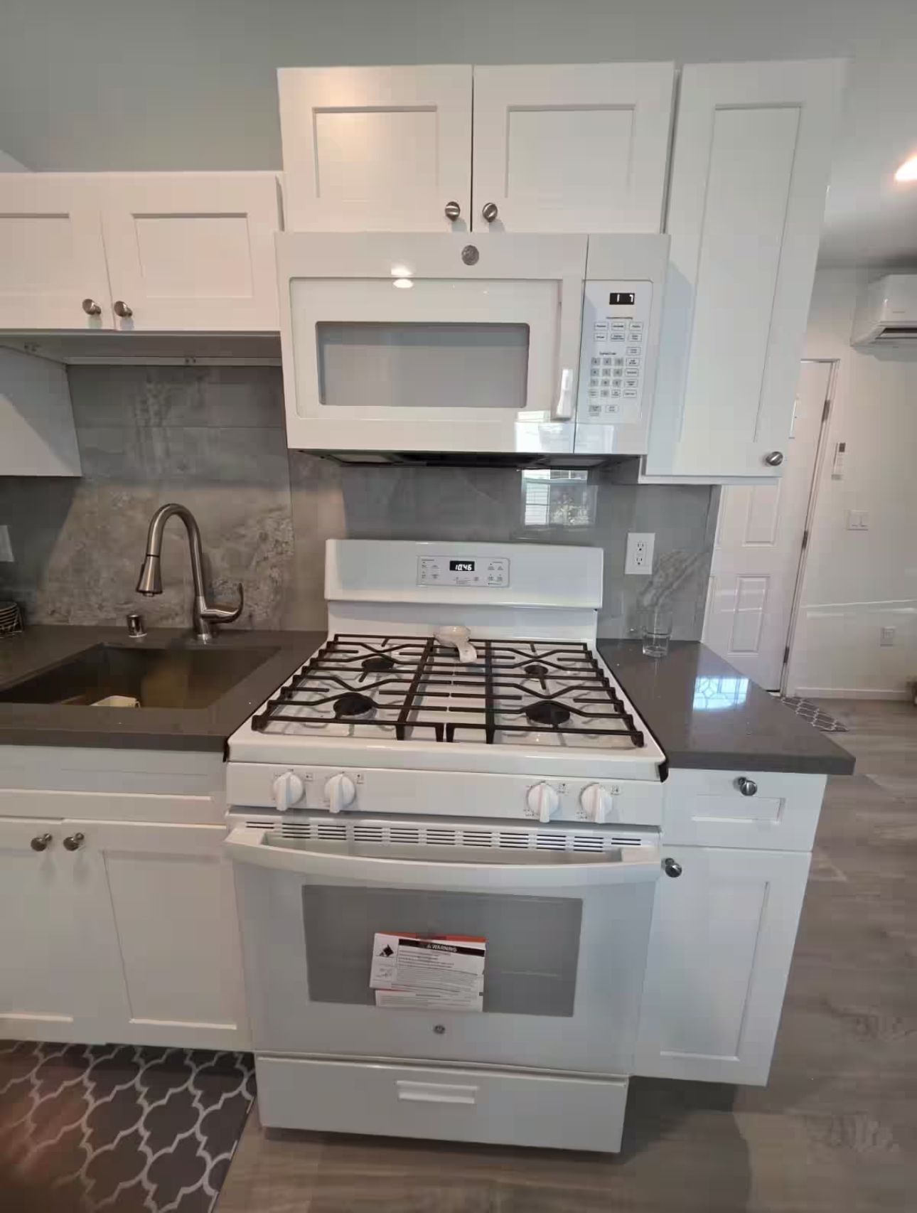 A kitchen with white cabinets, a microwave, a stove, and an oven.