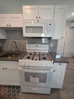 A kitchen with white cabinets, a microwave, a stove, and an oven. - Private Porter Ranch Gem-Parking & Near CSUN (Los Angeles)