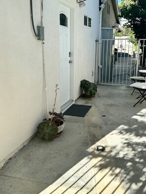 A concrete patio with a white door, a potted plant, and a metal gate. - Private Porter Ranch Gem-Parking & Near CSUN (Los Angeles)