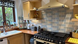 Une cuisine compacte équipée d’une cuisinière à gaz, d’un four et d’un crédence carrelée.