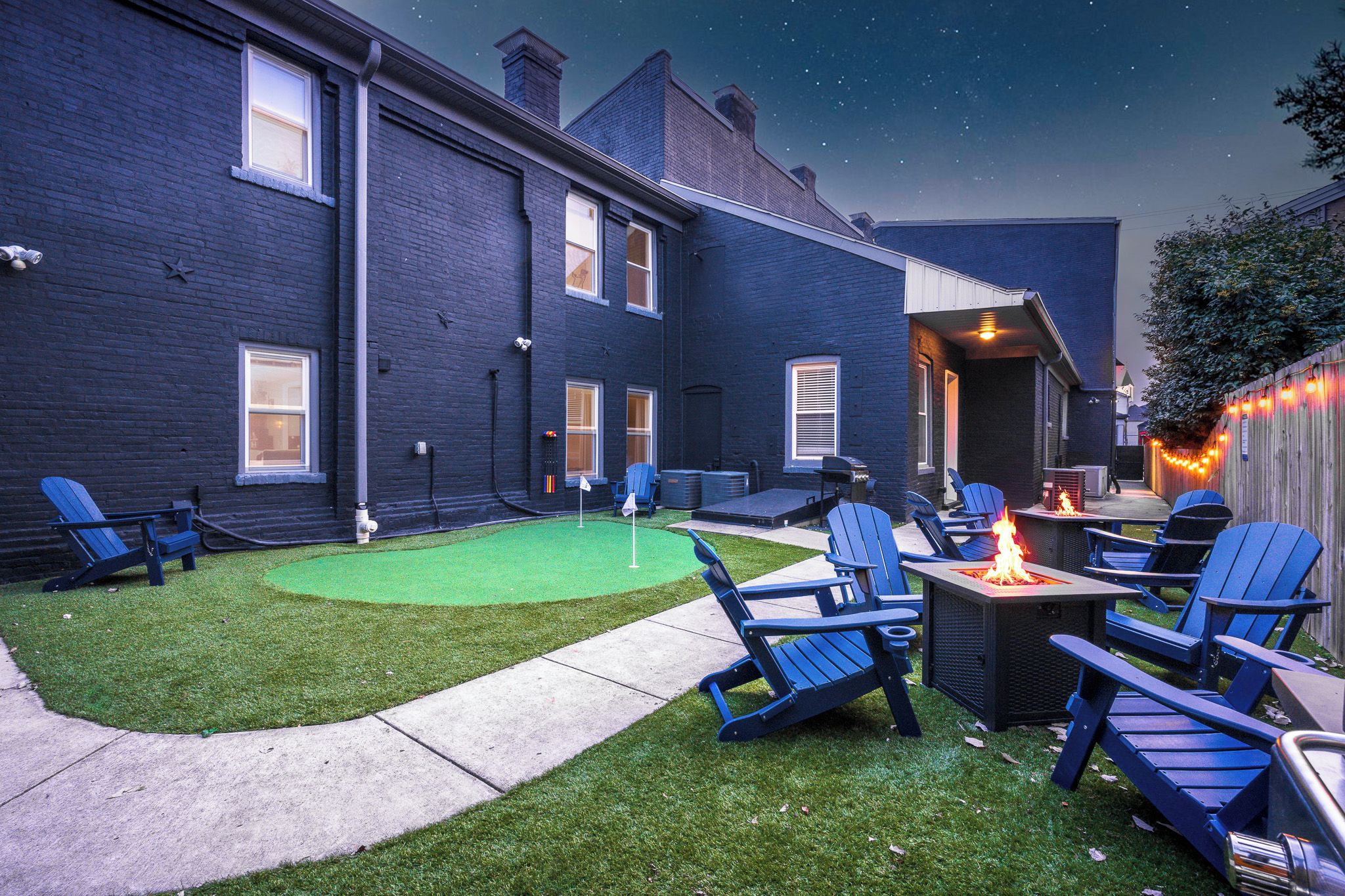 A backyard with a fire pit, outdoor seating, and a well-maintained lawn.