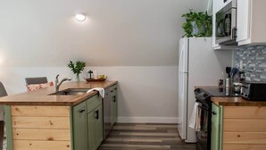 Une cuisine de taille réduite, avec des meubles de rangement en bois, un évier, une cuisinière et un four à micro-ondes.