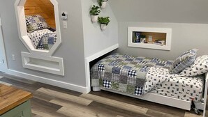 Une chambre avec un lit de style industriel, un miroir encastré et une étagère de chevet avec des livres et des plantes.
