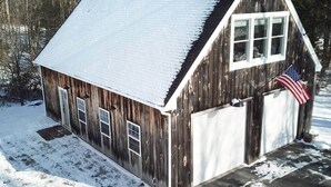 Une grange en bois avec un toit en métal, deux portes de garage et un drapeau américain.