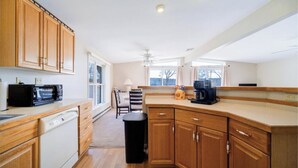 A kitchen with wooden cabinets, a microwave, a dishwasher, and a coffee maker. - Catskills Lakefront Getaway at Sackett Lake (Monticello)