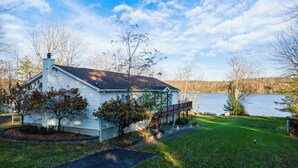 A single-story house with a porch, a small deck, and a pathway leading to the front door. - Catskills Lakefront Getaway at Sackett Lake (Monticello)