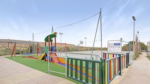 A playground with a slide, climbing structures, and a fenced area.