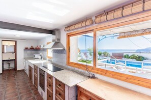 Cuina amb un finestra gran que dona a una piscina i vistes al mar.