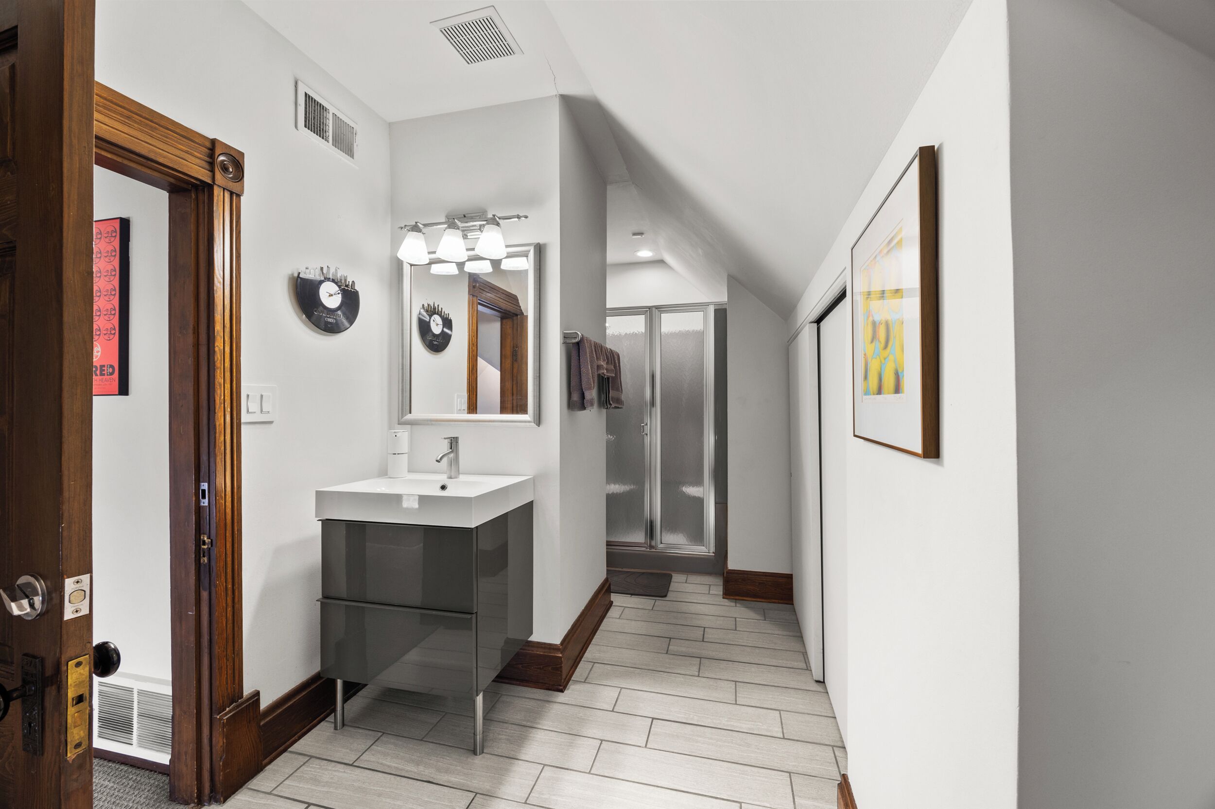 A modern bathroom with a vanity, mirror, and shower.