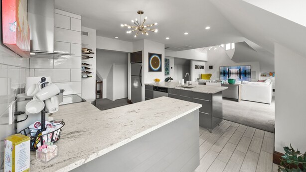 Una cucina moderna con mobili bianchi, un'isola centrale e un lampadario contemporaneo.