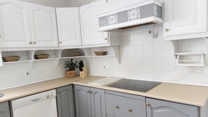 Ett kök med vita skåp, en diskmaskin och en svart bänkskiva.