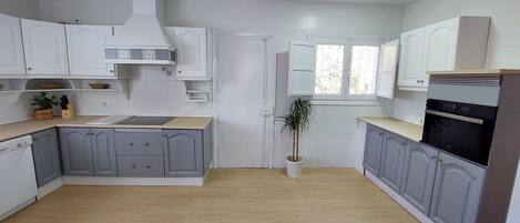 A modern kitchen with white cabinets, a built-in oven, and a wooden floor.