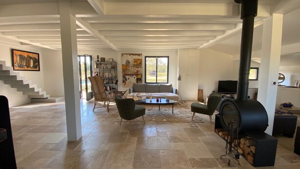 A spacious living room with a fireplace, a bookshelf, a sofa, and a staircase.