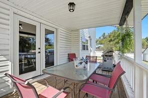 A covered patio with a table and chairs, a grill, and a sliding glass door.