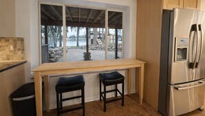A kitchen with a large window, a stainless steel refrigerator, and two bar stools. - All-Sports Lakefront Retreat w/ Private Beach, Dock & Tiki Bar - Sleeps 10 (Linden)