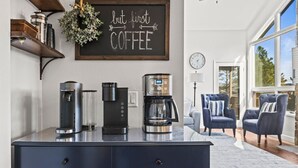 Una cucina moderna con un angolo caffè, una lavagna e vista sull'area soggiorno.