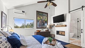 Camera moderna con un letto grande, una TV, un caminetto e vista sull'esterno.
