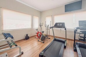A gym with exercise equipment, including treadmills and dumbbells. - Nagoya One Hotel (Batu Ampar)