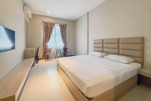 A modern hotel room with a large bed, a flat-screen TV, a desk, and a chair.