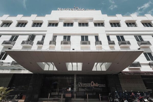 Un hotel con fachada moderna, varios balcones y una zona de entrada cubierta.