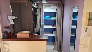 A room with a wooden counter, a mirror, a wardrobe, and shelves with folded clothes. - La Villa verte (Robert)