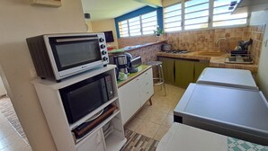 A compact kitchen with a microwave, oven, and a small gas stove. - La Villa verte (Robert)