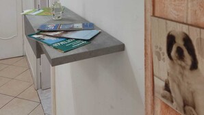 A hallway with a grey console table holding magazines and a bottle. A mirror reflects a door and a wall-mounted coat rack. - The Ideal Shelter for Families "Discover the heart of Mesagne (Mesagne)